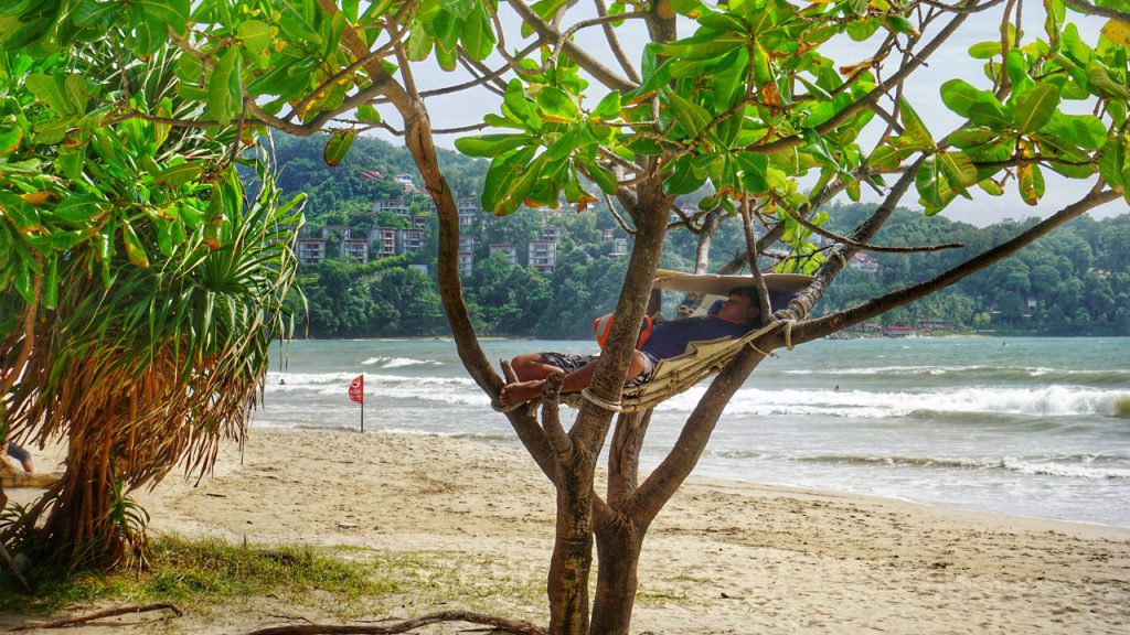 Người đàn ông nghỉ ngơi trên cây ở bãi biển Patong